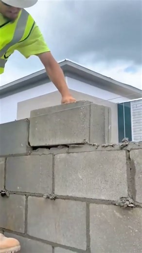 building a tall gray wall with large concrete blocks and wet mortar for a strong house structure