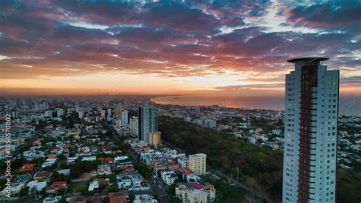 Fast hyperlapse drone zoom in over Santo Domingo city during sunrise with soft clouds and morning colors.