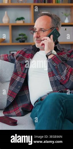 Happy senior man sitting on sofa at living room and talking on the smartphone. Mature male speaking with grandchildren, enjoying phone conversation at home. 4k Stock Video Footage - Alamy