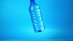 Super slow motion of the water bottle falls and spills. Filmed on a high-speed camera at 1000 fps.On a blue background.