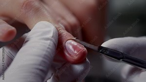 Manicurist cuts customer cuticle with sharp scissors in beauty salon closeup. Beautician in gloves removes thin skin strip from nail in shop. Manicurist takes care of young woman hands at procedure