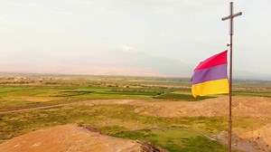 Close aerial view Armenian flag in windy day outdoors with countryside and Ararat mountain background