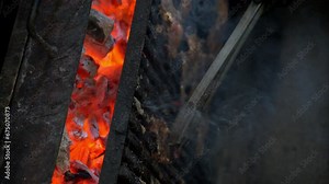 Slow motion of a cook wearing black gloves turning around juicy beef meat steaks on a grill using grill tongs. Vertical shot. Delicious