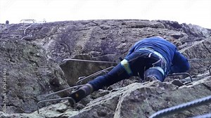Man in body harnesses feature life-safety, attaches hooks to iron brackets, climbs rock, active lifestyle of people, mountaineering, viaferrata in mountains of pyrenees, High quality 4k footage