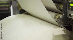 Machine pulls and twists large paper roll in printing house