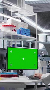 Vertical Green screen on pc on desk next to researchers team working in lab with research tools. Clinical experiment emphasizes molecular biology, innovation and biotechnology for advanced discovery. Camera A.