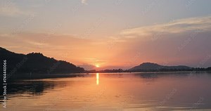 As the sun sets, Dal Lake bathes in a mesmerizing orange hue, its reflective surface capturing the stunning beauty of the passing boats.