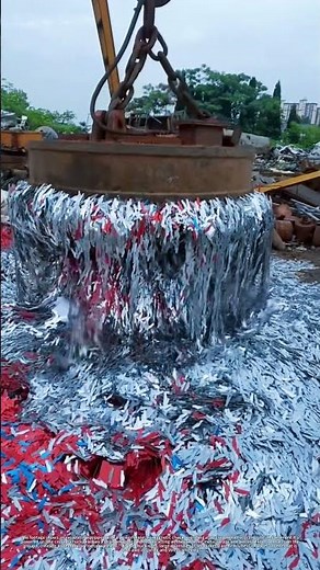 Excavator with an electromagnetic chuck moves metal scrap at a recycling yard.