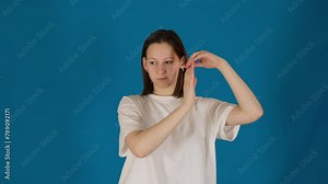 Concentrated young woman performs basic arm wave movement. Focused lady in t-shirt does relaxation exercise to cope with problems