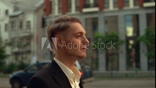 side view profile successful young businessman walk down the street, caucasian man walking along the road outdoors. on background cars are passing by