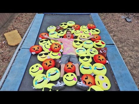 Athletes jump on trampoline covered in various emoji pillows