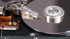 Rotating spindle, swinging read-write arm, magnetic platter, inside of hard drive, computer technology. Close up, 4K Ultra HD.