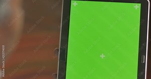 Black hand tapping, and scrolling on a digital tablet green screen display