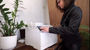 A middle-aged woman works in an office on a copy machine. An office manager puts paper into a printing copier. Working with a printer and printing documents