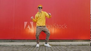 Playful crazy man dance emotions. Dancing man funny break dance, happy rhythmically waving his arms against red textured street wall. Breakdancing, street dancing, hiphop, freestyle dance. Lifestyle