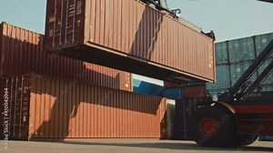 Modern Container Handler Carrying a Large Red Steel Shipping Cargo Storage Container in a Shipyard Terminal. Driver Operating the Handling Equipment is Loading the Crate in the Logistics Center.