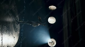 Young woman figure skating coach skates on dark ice arena. Silhouette of female figure skater practicing rotation and sliding skills. Figure skating training. Skill practicing. Slow motion. Vertical v