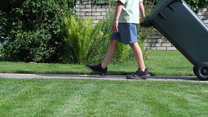 Download boy rolls out trash can. Boy throws out garbage. Child helps with chores for free