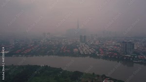Aerial view of air pollution in southeast asian city. Location is Ho Chi Minh City, Vietnam with Saigon River and city skyline. Flying in over river towards Thao Dien.