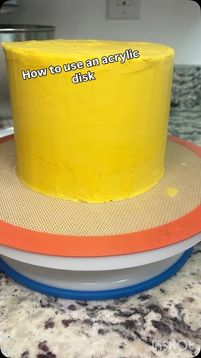 Acrylic disks are super easy to use and they make getting even and smooth sides a piece of cake 😉 it’s best to have a disk that’s just a little bigger than your cake size. Here my cake is a six inch, and the disk is 6 1/4”. Use the straight spatula to attach the disk at the top edge of the cake all the way around and then even it out down the sides. Use a straight scraper all the way around to smooth it. To get a nice crisp edge at the top, freeze for about 10 minutes before using a paring knif
