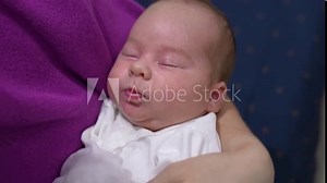 Cute child sleeping sweetly and pressing his tiny lips in his sleep. Adorable baby boy is resting peacefully in his mother’s hands. Close up.