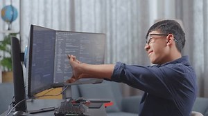 Asian Boy Programmer Stretching While Creating Software Engineer Developing App, Program, Video Game On Desktop Computer At Home. Terminal With Coding Language