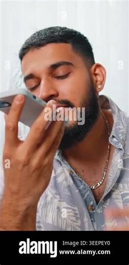 Happy excited Indian man making phone call conversation with friends at modern home room apartment. Arabian guy enjoying mobile loudspeaker talking gossip, rumors, good news sitting on couch indoors Stock Video Footage - Alamy