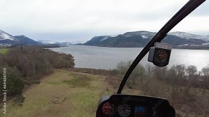 Helicopter cockpit inside view shot departing taking off from field towards a lake water valley