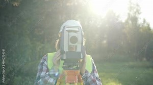 Engineer Topographer woman performs engineering survey and topography work on a sunny day, geodetic work, topography, land surveying, cadastral work.