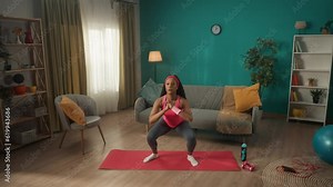 African American woman doing sit ups during a sports workout in the living room. The woman stands up and shakes her legs in turn, letting her muscles relax. Slow motion.