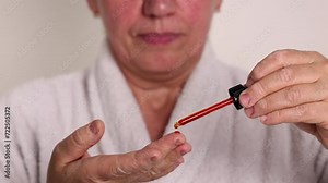 elder woman doing facial care daily routine procedure.granny applying serum,cream,remove makeup with cotton disk.female with towel on head and mask sheet on face is drinking coffee,wellbeing.