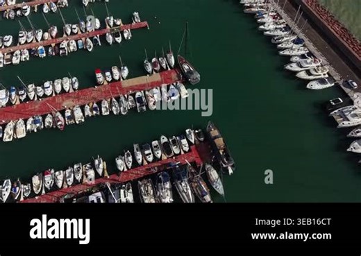 Marina shows many boats lined up on docks. The water is green as sunlight reflects off the surface. The scene captures an active area for boating activities and leisure Stock Video Footage - Alamy
