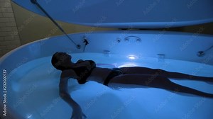 Young Woman in float tank, sensory depravation tank at spa