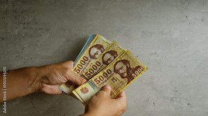 Hands holding hungarian forint banknotes against a concrete background, displaying various denominations of the currency.