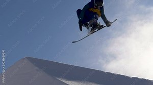 Slow motion - Freestyle skier jumping off kicker, grabbing ski and doing a spin at snow park