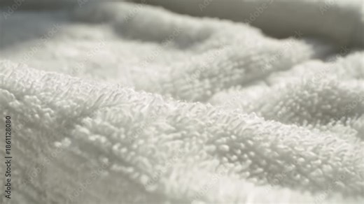 Soft white towel texture close up showing plush looped cotton textile fabric and gentle folds creating cozy calm feeling bath linen tactile scene