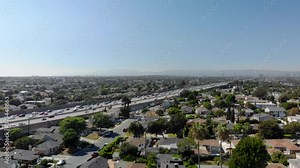 Aerial over neighborhood overlooking traffic on Interstate 405 with mountains in the background, the San Diego freeway, bright, sunny day, in Los Angeles, California, USA - Tracking, drone shot