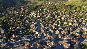 Verbier, Switzerland: Aerial drone footage of the famous Verbier mountain village with luxury chalets and the modern church in the Swiss alps in summer.