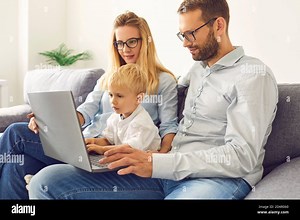Young family staying home, and using laptop for video calls, watching movies, or online shopping Stock Photo - Alamy