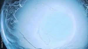 Translucent blue liquid forms swirling patterns in a clear glass bowl, creating an artistic display of water movement and texture