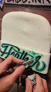 Painting a super simple script name design on a custom beanie. Would you wear it? #airbrush #90s #y2k #oldschool #retro #handlettering #cursive #calligraphy #art #fyp | Dale the Airbrush Guy
