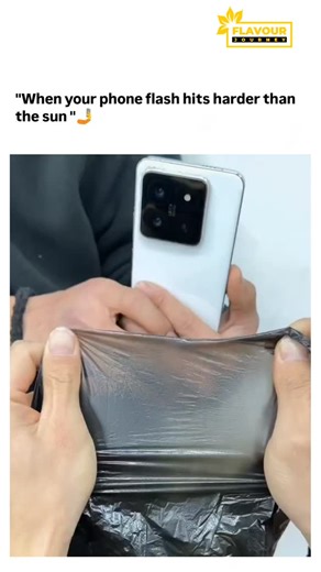 Flavour Journey on Instagram: "The video in the post shows a Samsung smartphone's LED flash held against black plastic wrap, rapidly melting a hole through it due to concentrated light energy converting to intense localised heat. This demonstrates a viral 2025 trend testing high-output phone flashes, like the Galaxy S25 Ultra's 200-lumen beam, which mimics solar ignition by focusing photons that plastics absorb and transform into thermal energy. Replies blend humour with insight, such as explana