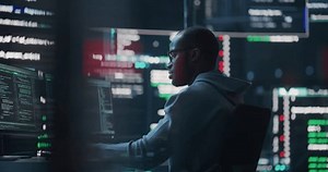 Dolly Shot of a Black Male Programmer Working in a Monitoring Control Room, Surrounded by Big Screens Displaying Lines of Programming Language Code. Portrait of a Man Creating a Software and Coding