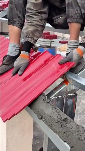 Installing the red roof panel carefully onto the cement ridge