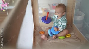 baby toddler plays with a toy pyramid sits in a crib arena. happy family kid dream concept. baby toddler development of fine motor skills plays lifestyle with pyramid rings in kindergarten