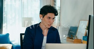 Young freelance Asia male use computer remote on desk and happy arm raised success result in living room at home office. Work from house, financial plan, remotely digital nomad job and Gen Z talent.