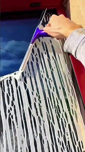 cleaning glass windows using a purple squeegee to remove soap and water for a clear and shiny finish