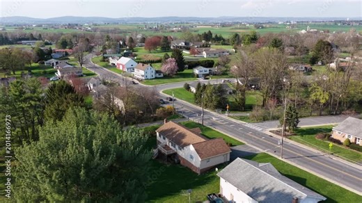Main street in Akron,Pennsylvania with residential homes, light traffic and surrounding farmland during spring season showing rural small town living and open landscape in United States. Aerial Wide.