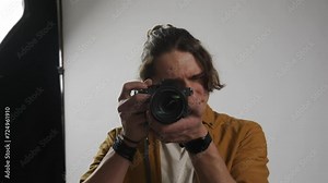 Model and production team in the studio. Man professional photographer taking picture looking directly at camera smiling.