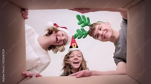 Happy Christmas family - mom, son and daughter opening cardboard box and looking inside. Woman and children unboxing gift - different versions of emotions. Holidays and New Year.